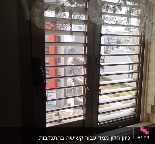 תריסי אלומיניום בחלון עם וילון תחרה